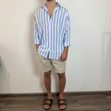 Camisa de lino de corte oversize con diseño de rayas verticales en tonos blanco y tostado, manga larga y cierre frontal con botones.