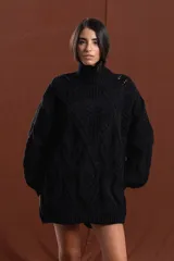 Buzo de tejido de punto grueso en color negro, con cuello alto y diseño de trenzas y relieves en toda la prenda. Presenta mangas largas con terminación ajustada y corte holgado.