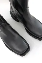 Bota corta negra de cuero, con cierre lateral y suela track.