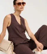 Chaleco entallado de mujer, color marrón oscuro con finas rayas verticales blancas (rayas de giz). Presenta escote en V, cierre frontal con botones forrados y bolsillos falsos.