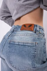Jean mom fit de tiro alto en color azul claro con lavado vintage. Presenta un corte relajado y tajos laterales en el ruedo de los tobillos.