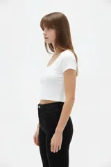 Top cropped de algodón blanco, al cuerpo, con mangas cortas y escote redondo amplio.
