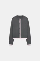 Chaqueta de punto de cuello redondo y manga larga, con cierre frontal de botones. Presenta un diseño en color gris con detalles en contraste de color rosado en el borde frontal, puños y ruedo.