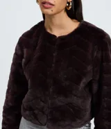 Saco corto de pelo artificial de marca Blue Steel, con textura de diseño chevron, cuello redondo, manga larga y cierre frontal mediante ganchos.
