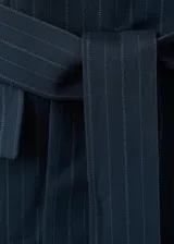 Blazer de doble botonadura color azul marino con estampado de raya diplomática, cuello en pico con solapa de muesca, bolsillos con solapa y diseño recto.