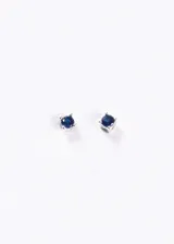 Par de aros tipo stud (perno) de plata 925, con una pequeña piedra zirconia redonda de color azul oscuro engastada en cuatro puntas.