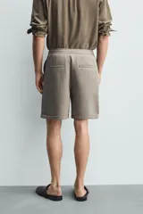 Bermuda regular fit de tejido elástico color blanco, con cintura elástica ajustable mediante cordón, bolsillos delanteros y bolsillos traseros de vivo.