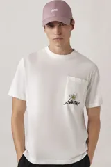 Remera blanca de corte clásico, con cuello redondo, mangas cortas y bolsillo en el pecho con estampado floral y logo de la marca.