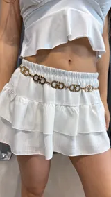 Cinturón dorado con eslabones con el logo de la marca y cierre de gancho.