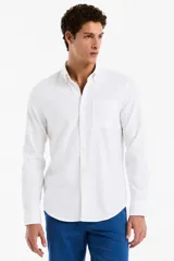 Camisa blanca de manga larga confeccionada en mezcla de lino y algodón, con cuello con botones, cierre frontal abotonado y un bolsillo aplicado en el pecho.