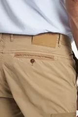 Pantalón cargo gris de gabardina, corte slim, con bolsillos laterales con solapa y bolsillos traseros con ojal y botón. Presenta efecto teñido en la tela.