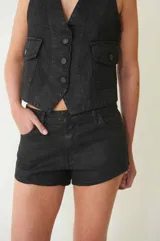 Short negro de tiro bajo, confeccionado en denim 100% algodón con proceso de encuerado. Tiene cuatro bolsillos, pasa cintos, cremallera y botón metálico.