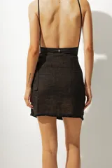 Falda corta tipo pareo con diseño envolvente, confeccionada en tela con estampado de rayas verticales en tonos tierra. Cuenta con un lazo lateral para ajuste y un borde inferior con detalle de costura en contraste.