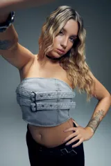 Top strapless de denim gris con diseño estilo corset, presenta doble tira ajustable con hebillas metálicas en el frente y cierre en la espalda.