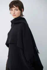 Ruana de tejido de punto en color negro, con diseño de cuello alto y terminaciones con flecos en los bordes.