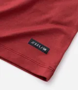 Remera deportiva de hombre en color rojo oscuro, con mangas cortas, cuello redondo y detalle de líneas negras en la manga. Confeccionada en poliéster con tecnología dry fit.