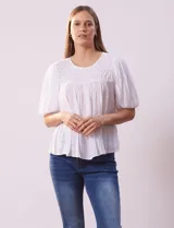 Blusa blanca de gasa marca Zac & Rachel, con frunces en la parte delantera, mangas cortas con puño elastizado, abertura central en la espalda y botón.