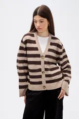 Saco de punto con diseño de rayas horizontales en tonos beige y marrón, cuello en V, cierre frontal con botones y bolsillos laterales. Presenta un corte holgado y mangas largas con puños acanalados.