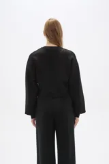 Buzo negro de corte cropped, con cuello redondo y mangas largas abullonadas.