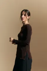 Top de manga larga con textura suave y leve brillo. Presenta una silueta al cuerpo, tajos laterales y terminaciones onduladas en el ruedo.