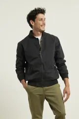 Campera tipo bomber color verde militar, confeccionada en 100% algodón. Cuenta con puños tejidos al tono, cuello y cintura elásticos, y cierre frontal metálico.