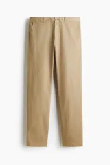 Pantalón de algodón color beige, estilo chino, con corte slim fit. Presenta cierre y botón frontal, bolsillos laterales al bies y bolsillos insertados con botón en la parte trasera.
