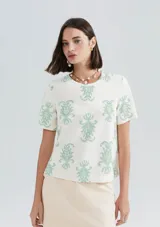 Blusa color blanco con estampado de flores color verde agua, de mangas cortas y cuello redondo.