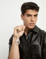 Llavero plateado con mosquetón grande y dije rectangular con el logo de la marca grabado.