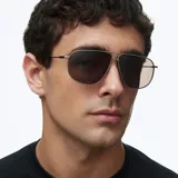 Lentes de sol estilo aviador oversize con montura metálica fina en color gris y doble puente. Lentes polarizadas en tono marrón con acabado pulido.