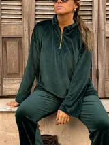 Buzo de pana color verde inglés, con cuello alto y cierre frontal parcial, de manga larga y diseño holgado.