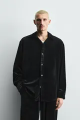 Sobrecamisa de corte relajado confeccionada en tejido de terciopelo elástico, con cuello solapa, manga larga con puños abotonados y cierre frontal de botones.