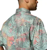 Camisa de manga corta Columbia modelo Super Tamiami, con estampado tropical de hojas en tonos verdes, rosados y naranjas. Presenta cuello abotonado, cierre frontal con botones y bolsillo en el pecho con logo de la marca.