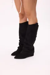 Botas de caña alta color negro, estilo texanas, confeccionadas en símil gamuza con efecto slouchy, punta afinada y suela cómoda.