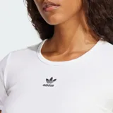 Remera corta ajustada al cuerpo, color blanco, de manga corta y cuello redondo, confeccionada en tejido acanalado. Presenta el logo del trébol de Adidas Originals bordado en negro en el pecho.