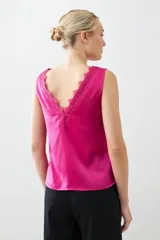 Top satinado color fucsia con escote en V y detalles de encaje en el borde del escote. Sin mangas y de corte holgado.