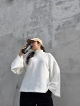Polerón de cuello alto en color blanco, con diseño de calce holgado y mangas amplias. Confeccionado en tela suave y abrigada, ideal para un estilo urbano y relajado.