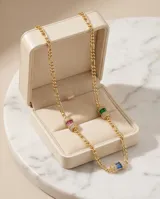 Gargantilla de plata 925 con baño de oro, compuesta por una cadena de eslabones y tres dijes cilíndricos decorados con circonias brillantes y piedras rectangulares en tonos verde y fucsia.