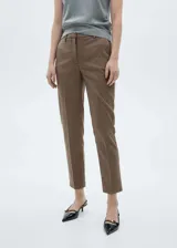 Pantalón de tiro medio con diseño crop, corte skinny y estampado a cuadros tipo tartán en tonos marrones y negros. Cuenta con trabillas en la cintura, bolsillos laterales y cierre oculto con botón, gancho y cremallera.