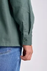 Sobrecamisa de color verde para hombre, con cuello clásico, cierre frontal de botones y dos bolsillos de parche en el pecho. De manga larga y corte recto.