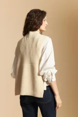 Chaleco de tejido de punto en color crema, con cuello alto y diseño acanalado. Presenta una silueta relajada con aberturas laterales.