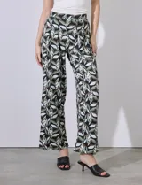 Pantalón largo de seda fría estampada con hojas en tonos verde, blanco y negro. Tiene pretina ancha elastizada.