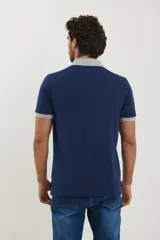 Remera azul con cuello y mangas con borde gris, corte clásico y bolsillo en el pecho.