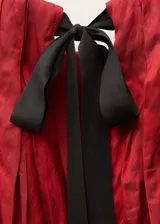 Vestido corto de cuello halter con diseño recto y fruncido en la parte superior. Presenta un cierre de lazo en la nuca y un acabado con textura sutil.