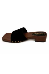 Zueco de inspiración artesanal marca Daniel Cassin, con base efecto madera y taco bajo. Presenta una capellada ancha de color negro con detalles de tachas metálicas doradas en los laterales.