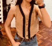 Chaleco color beige de pana con botones y ribete de cuentas negras.