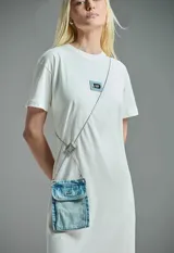 Vestido blanco de corte recto y manga corta, con logo estampado en el pecho y bolso bandolera de denim claro con cadena plateada.