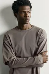 Camiseta de corte relajado confeccionada en algodón con elasticidad, con cuello redondo y diseño de manga larga con efecto doble. Presenta un acabado con efecto lavado.