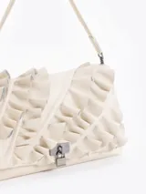 Cartera de hombro negra confeccionada en cuero vacuno, con diseño de solapa frontal decorada con volados de cuero y cierre metálico tipo candado.