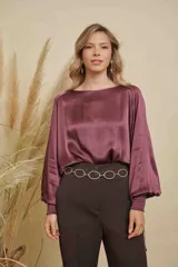 Blusa de satén color bordó con cuello a la base, mangas largas anchas y puños elásticos con detalle bordado.