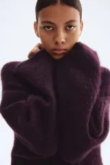 Buzo de punto oversized color morado oscuro, con textura suave y peluda, cuello redondo y hombros caídos.